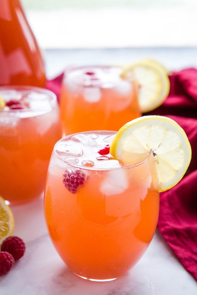 3 vasos de ponche de fiesta fácil con rodajas de limón, hielo y frambuesas