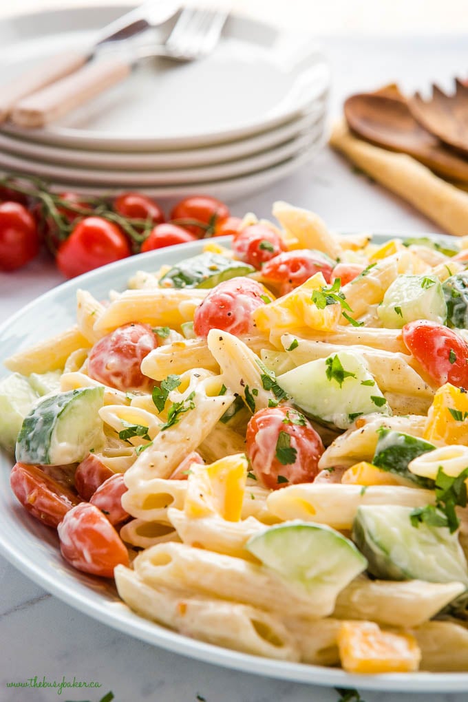 pasta salad with penne, tomatoes, cucumbers and yellow peppers in a pale blue bowl