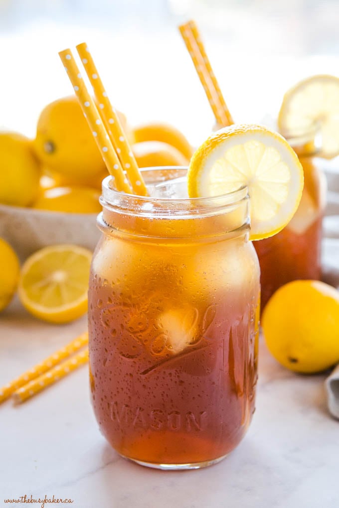 cold iced tea in Ball mason jar with lemon slice and 2 yellow straws