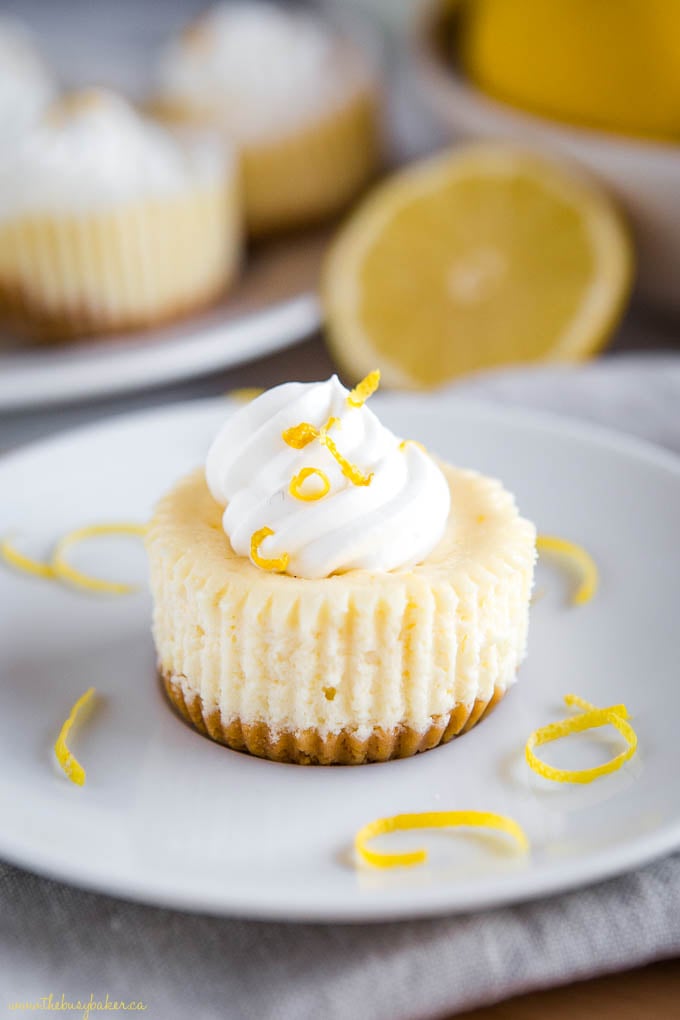 mini lemon cheesecakes on plate with whipped cream and lemon zest