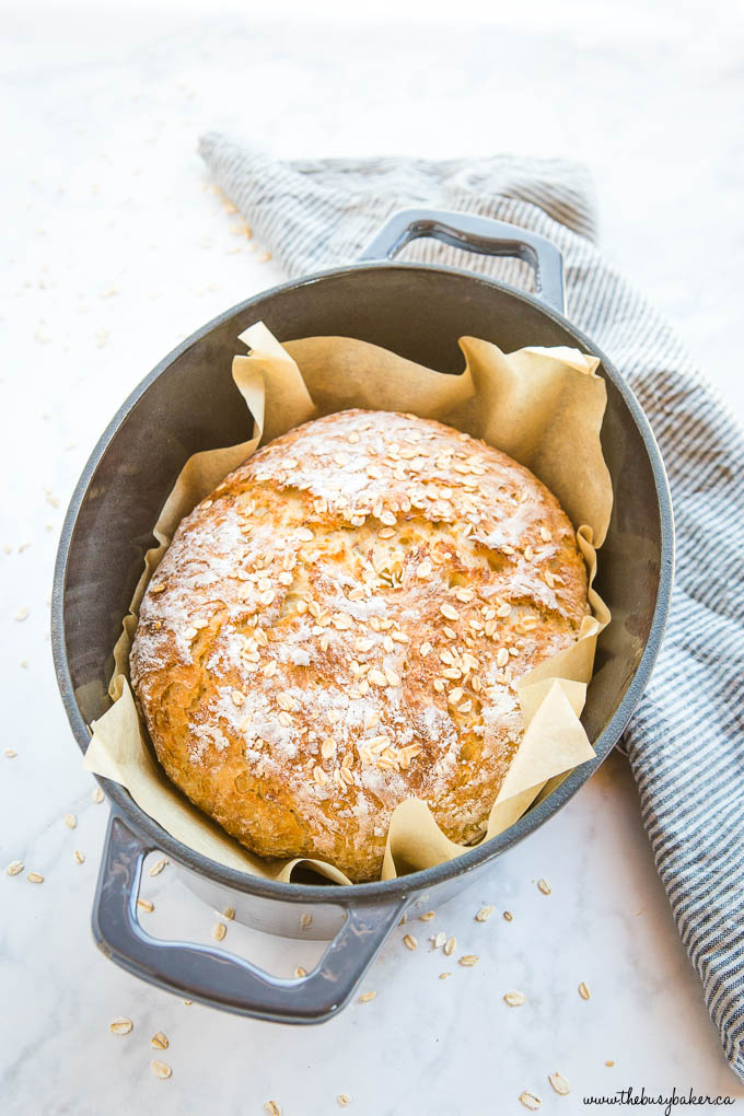 loaf of honey oat no knead artisan bread in black cast iron pot