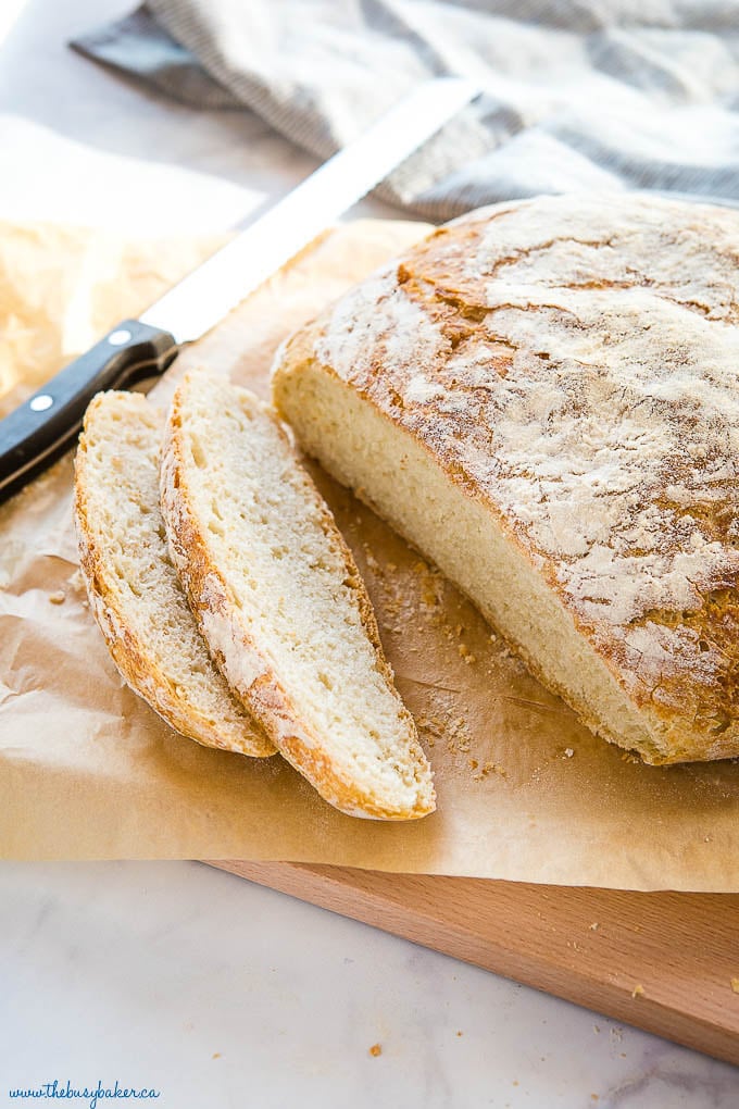 loaf of crusty bread sliced on cutting board with knife