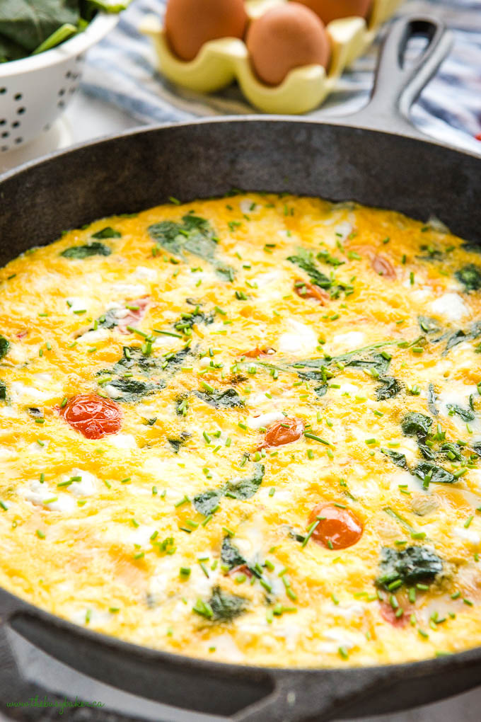 tomato spinach frittata in cast iron skillet with spinach and eggs
