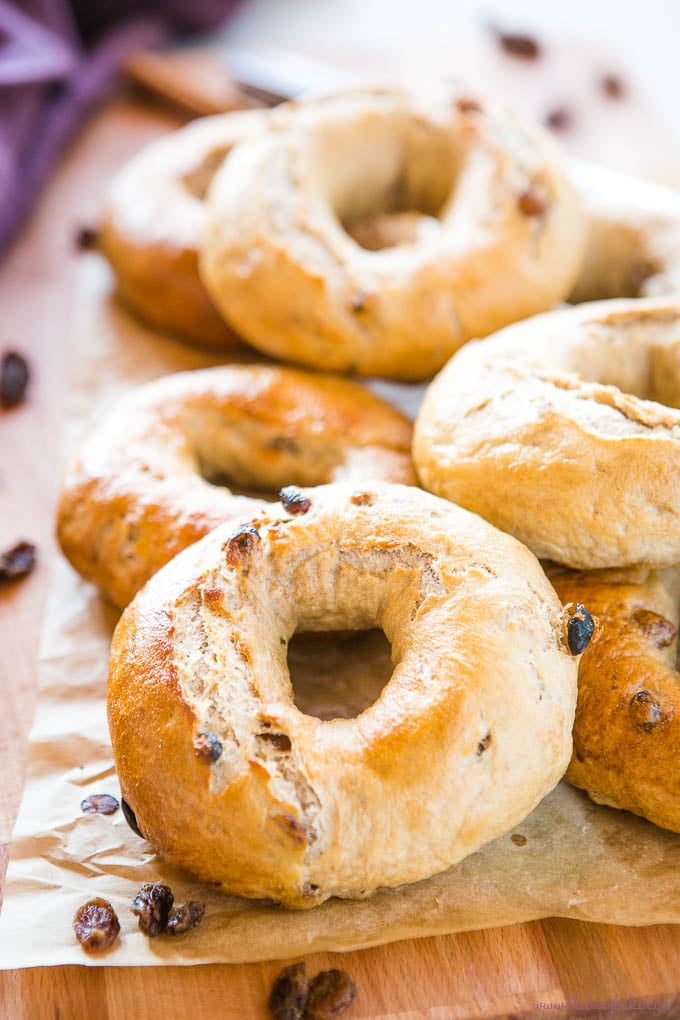 Cinnamon Raisin Bagels on wood cutting board with knife and cinnamon sticks