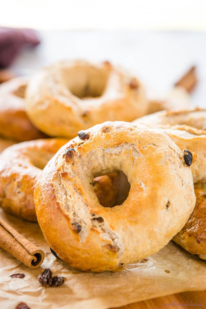 Cinnamon Raisin Bagels on wood cutting board with knife and cinnamon sticks