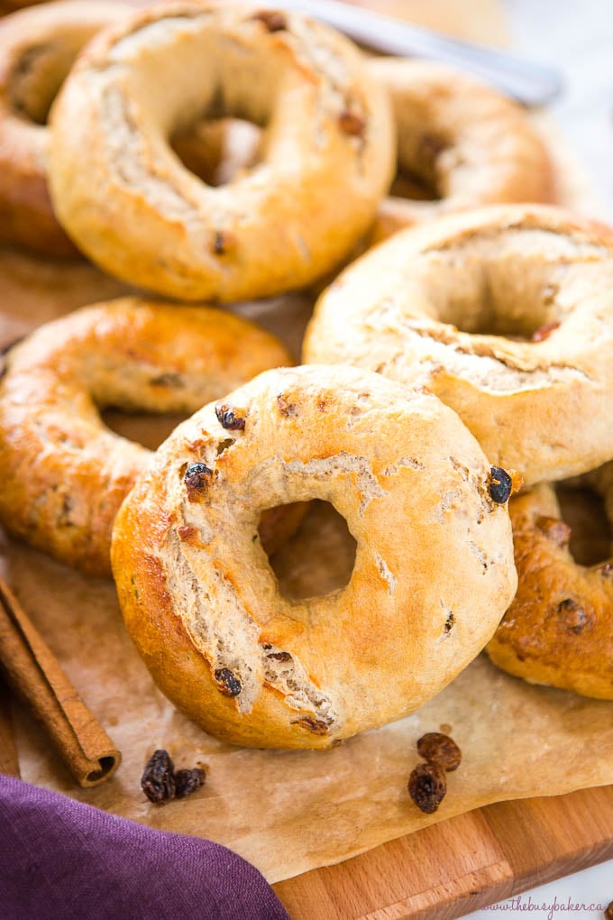 Cinnamon Raisin Bagels on wood cutting board with knife and cinnamon sticks