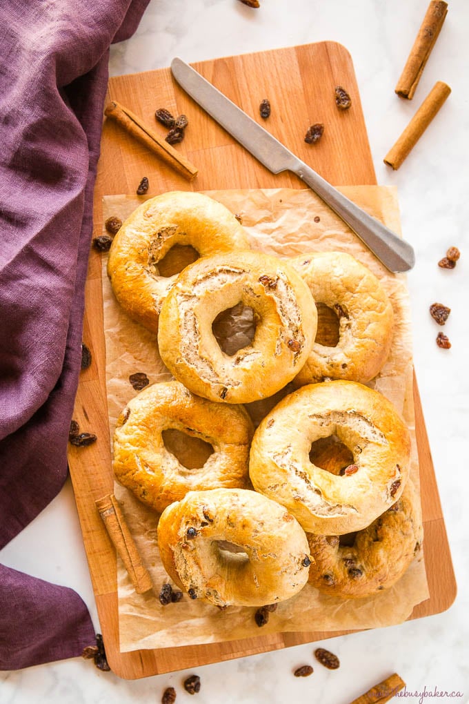 Cinnamon Raisin Bagels on wood cutting board with knife and cinnamon sticks