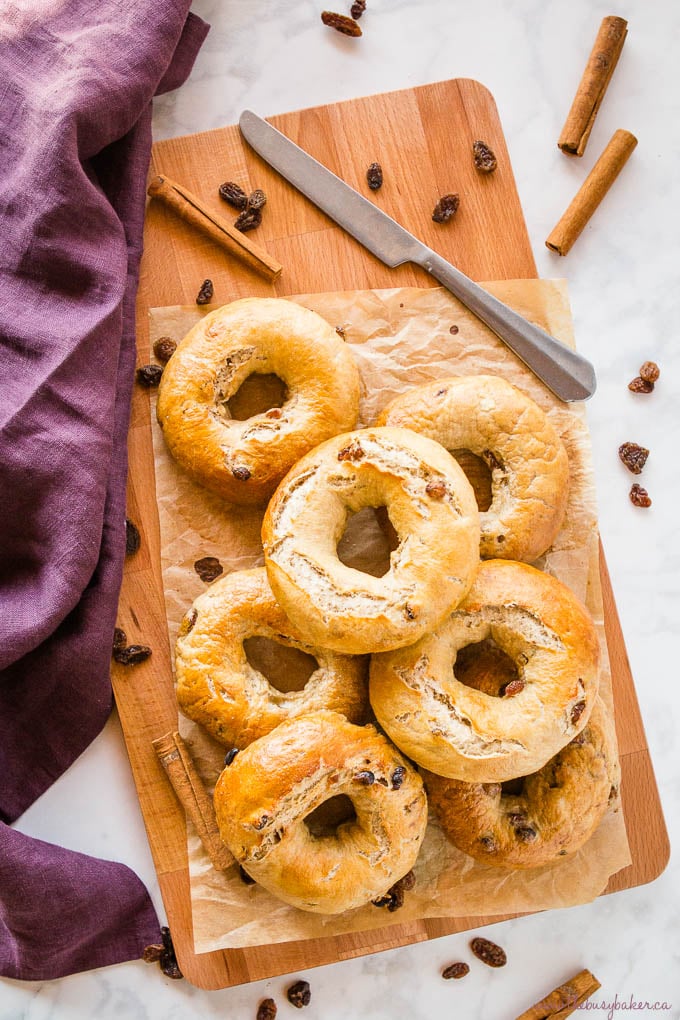 Cinnamon Raisin Bagels on wood cutting board with knife and cinnamon sticks