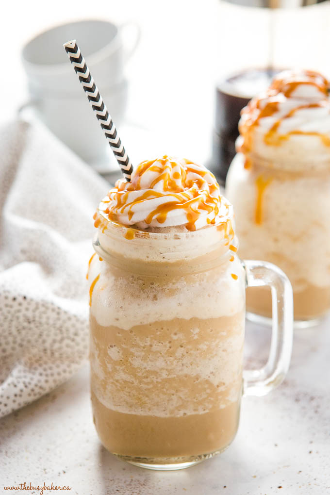 caramel frappuccino in mason jar mug with whipped cream, caramel sauce and paper straw