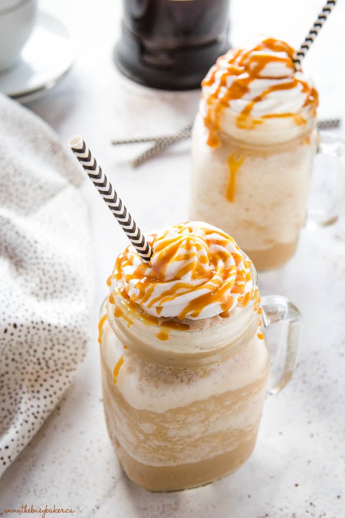 homemade caramel frappuccino in mason jar mugs with whipped cream and caramel sauce