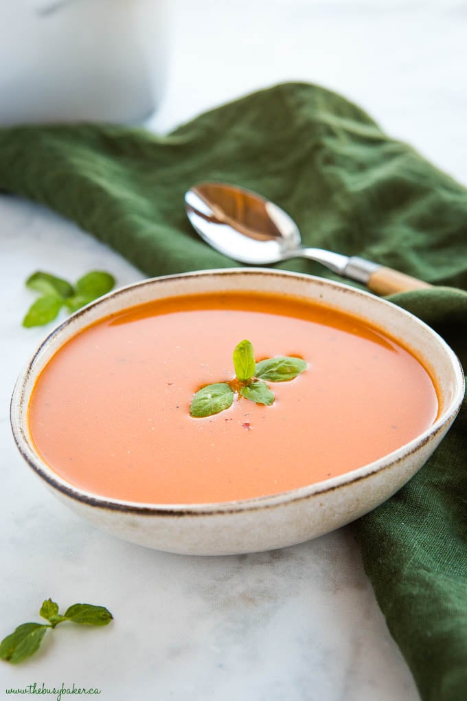 bowl of creamy tomato soup with basil leaves and spoon