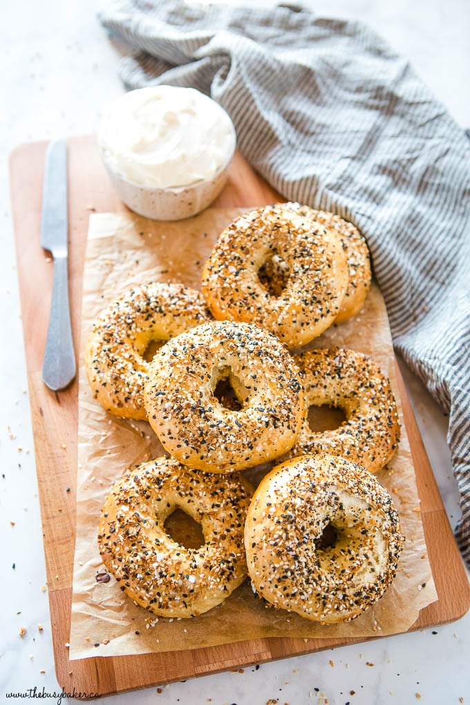 homemade everything bagels on wood cutting board with cream cheese and knife