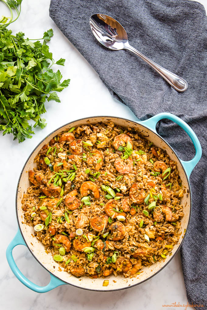 homemade shrimp fried rice in turquoise pan with spoon and fresh herbs