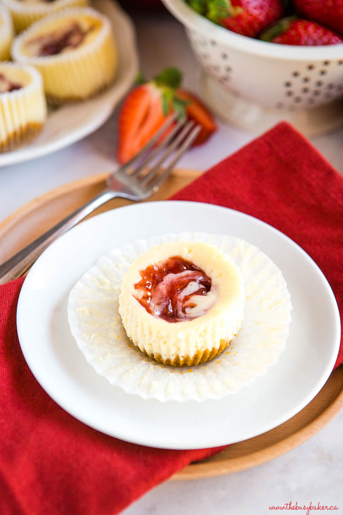 strawberry swirl mini cheesecake on white plate with fork and red napkin