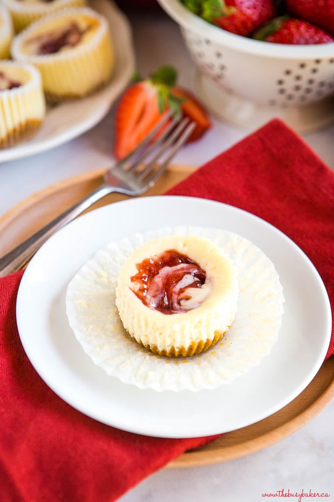 strawberry swirl mini cheesecake on white plate with fork and red napkin