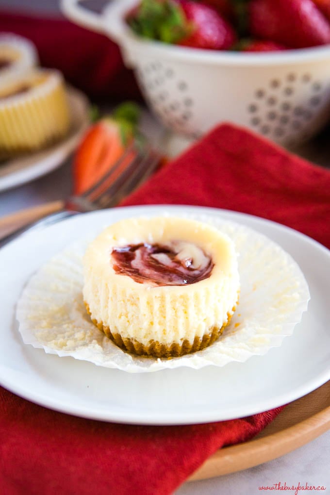 mini strawberry swirl cheesecake on white plate with red napkin