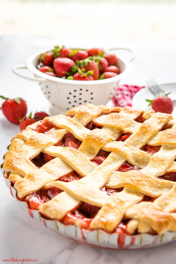 baked strawberry pie in aluminum old fashioned pie dish with fruit juice dripping down the sides