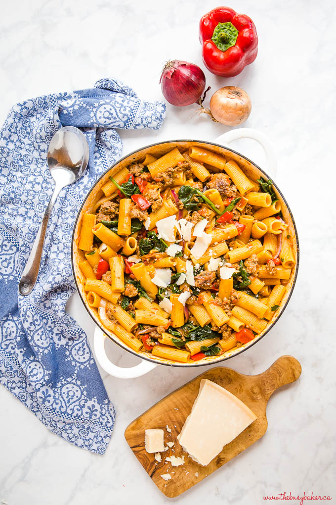 Italian sausage pasta with peppers and spinach in white cast iron pan