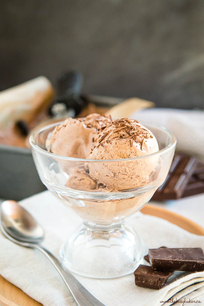 scoops of chocolate ice cream in glass dish with spoon and shaved chocolate