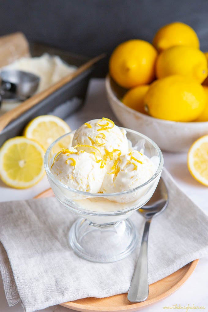 3 scoops of lemon ice cream in glass dish with spoon on wooden tray