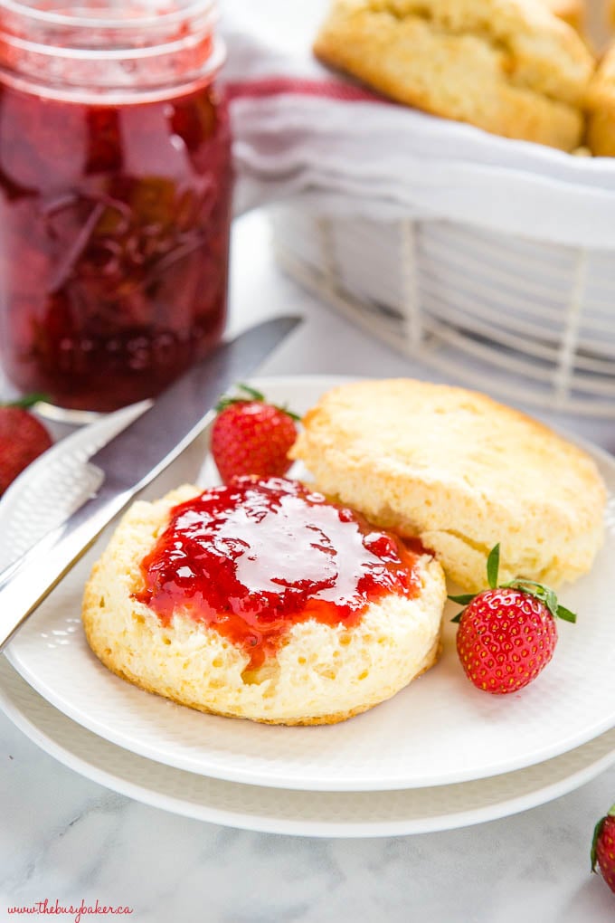 scone on white plate with strawberry jam