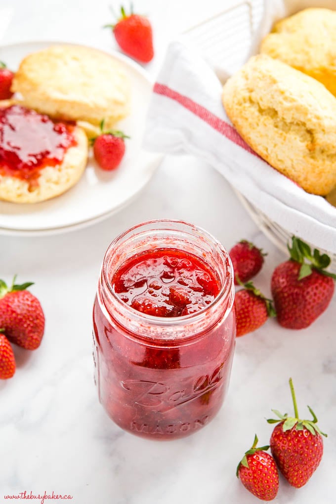 beautiful strawberry jam in mason jar with scones and fresh strawberries