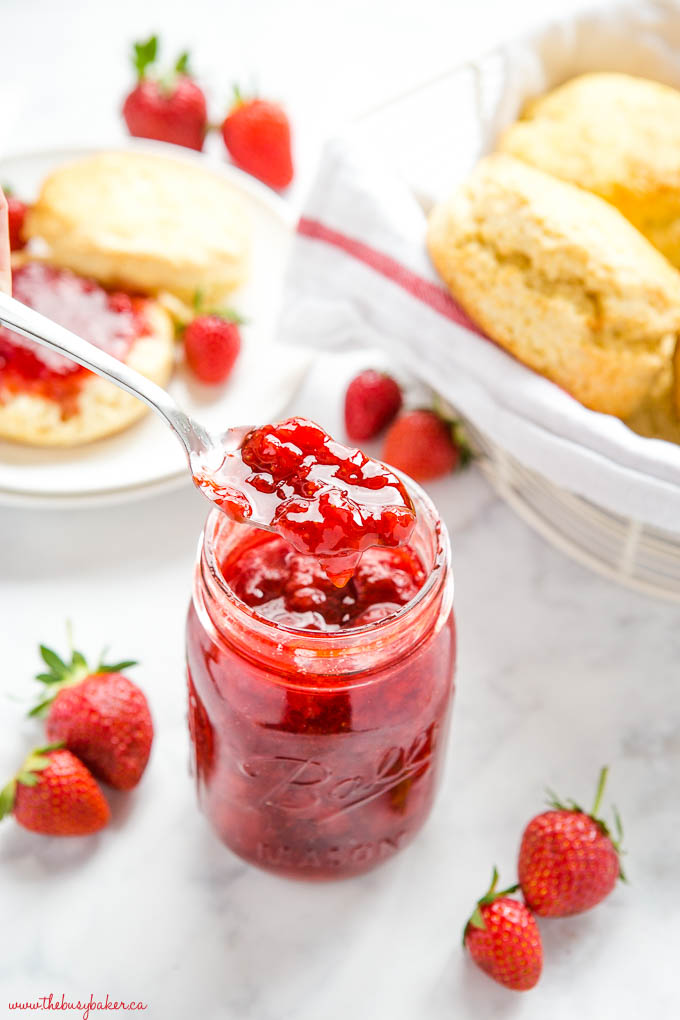 spoonful of strawberry jam with scones and fresh strawberries