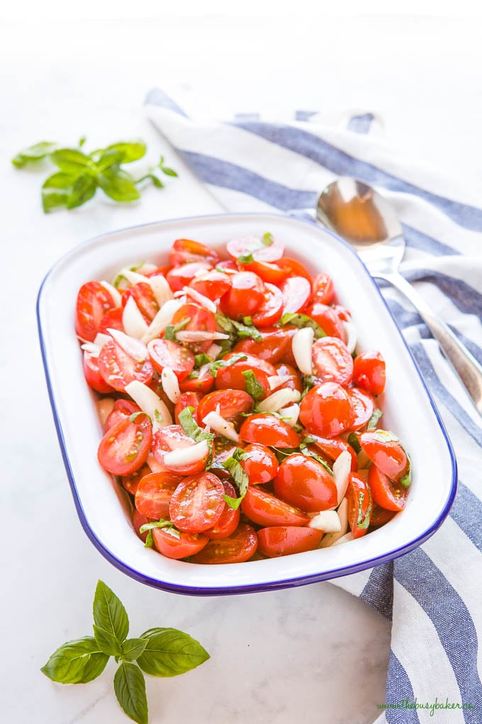 tomato onion salad with fresh basil in white enamel dish