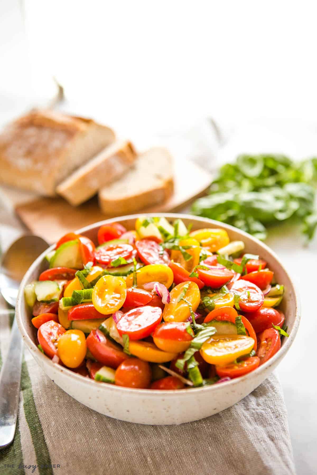 tomato cucumber salad in a pottery bowl with basil