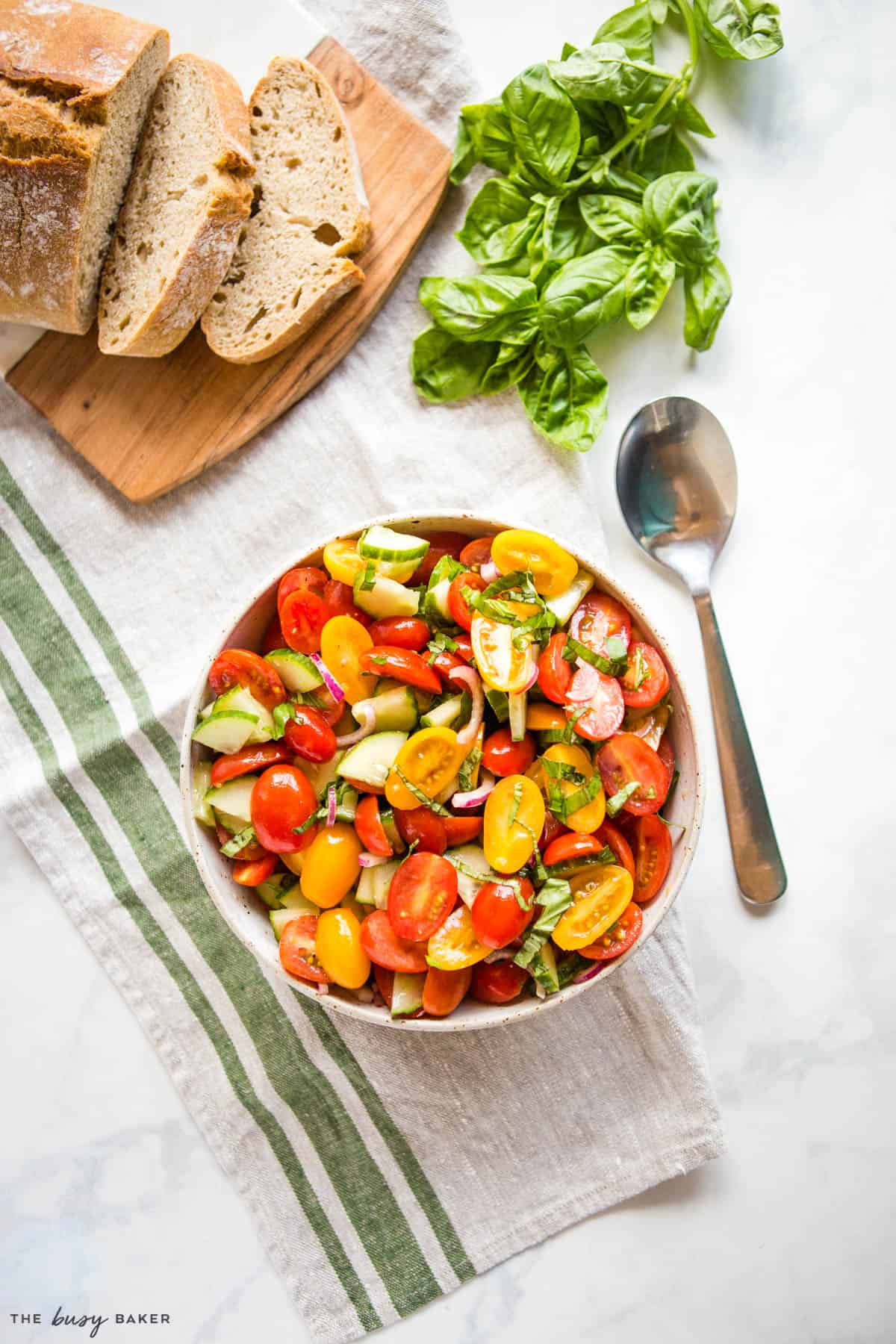 overhead image: tomato cucumber salad in a bowl with fresh basil