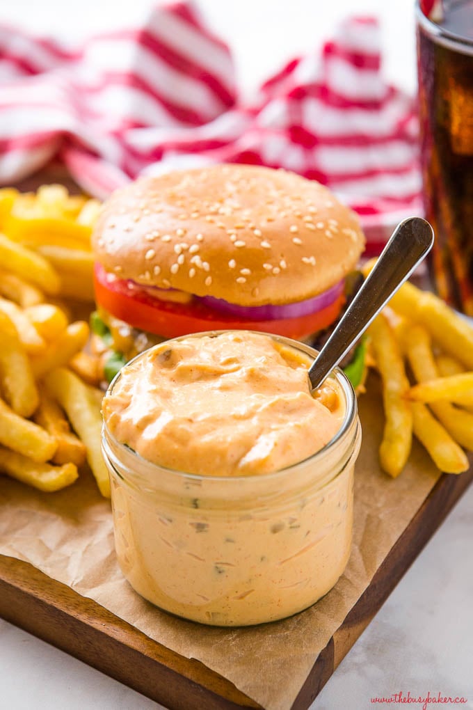 jar of homemade burger sauce with a spoon on platter with burger and fries