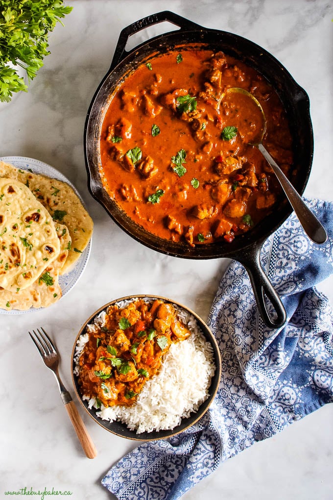 cast iron skillet with butter chicken and fresh cilantro, a plate of naan bread and a bowl of butter chicken over rice