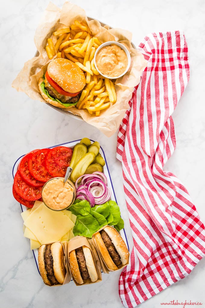 overhead image: cheeseburger platter with french fries, and 3 hamburgers with fixings on platter