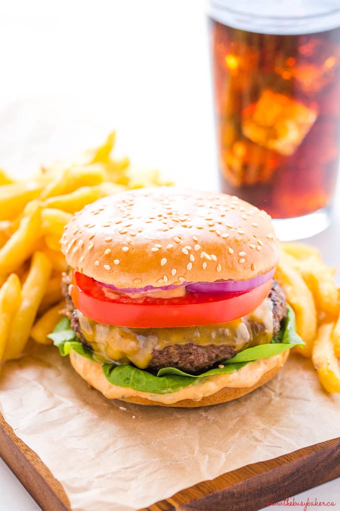 homemade cheeseburger on sesame seed bun with fries and coke with ice