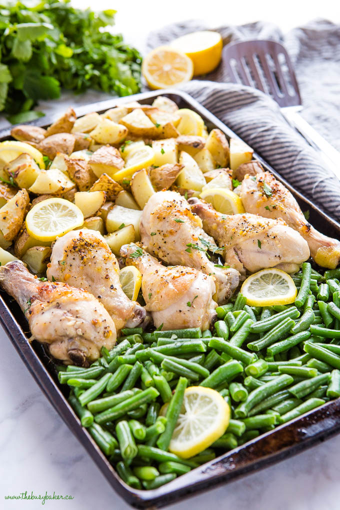 sheet pan with green beans, lemon slices, chicken drumsticks and potatoes