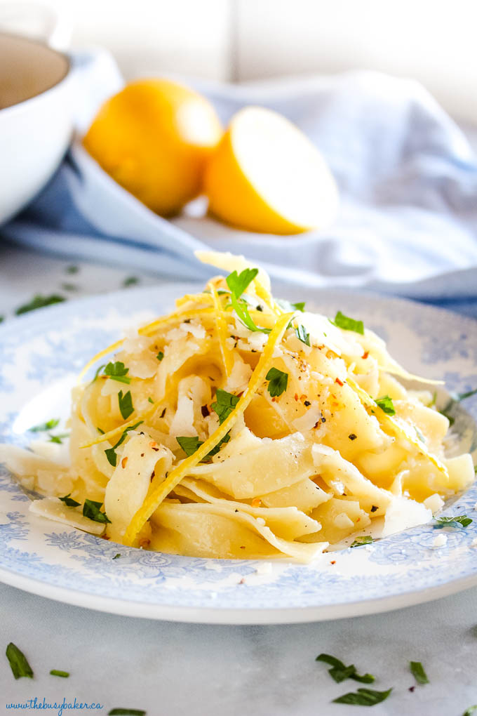 pasta al limone on white and blue plate with lemon zest, parsley and black pepper