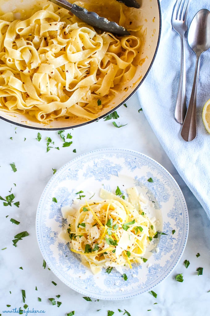 overhead image: pasta al limone in white cast iron pan and on blue vintage plate with fresh herbs