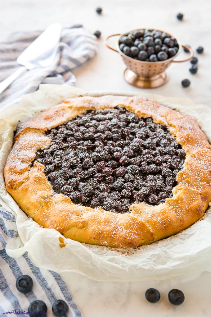 blueberry galette on crumpled parchment paper with fresh blueberries