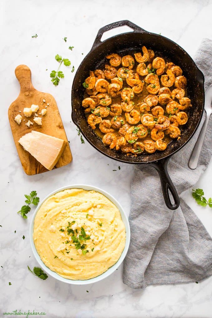 overhead image: cast iron skillet with cajun shrimp with a bowl of creamy parmesan polenta