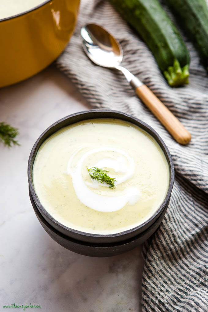 creamy zucchini soup in black bowl with fresh dill