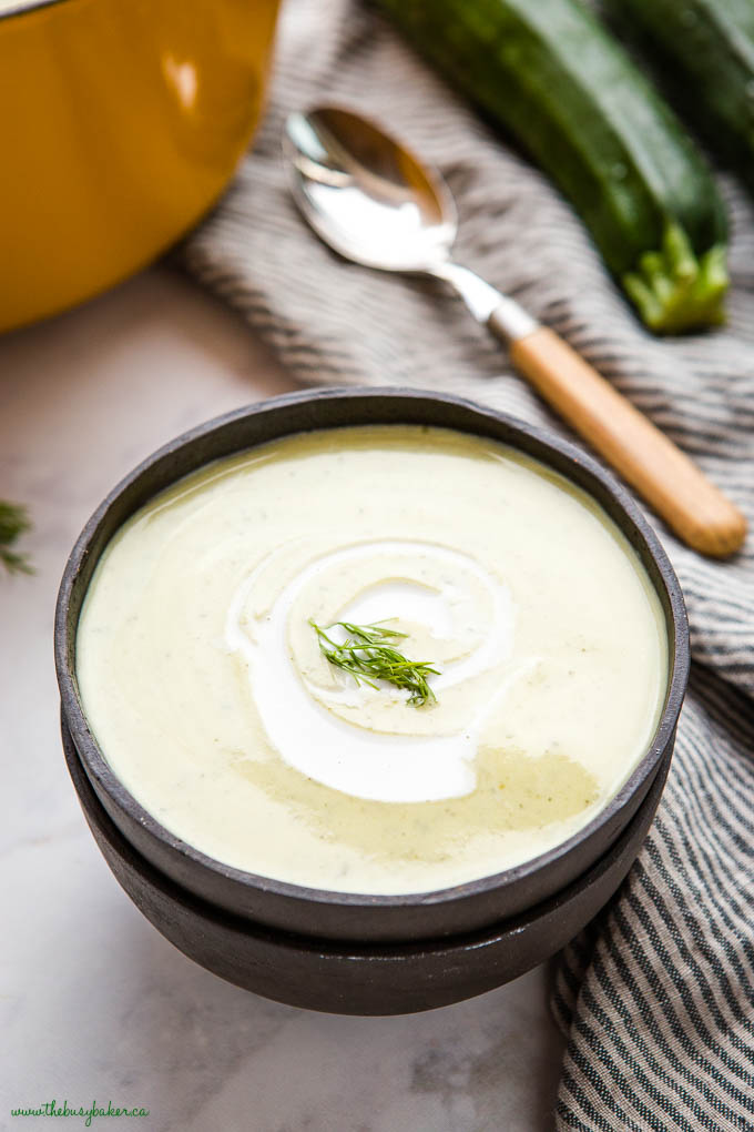 creamy zucchini soup in black bowl with fresh cream and dill
