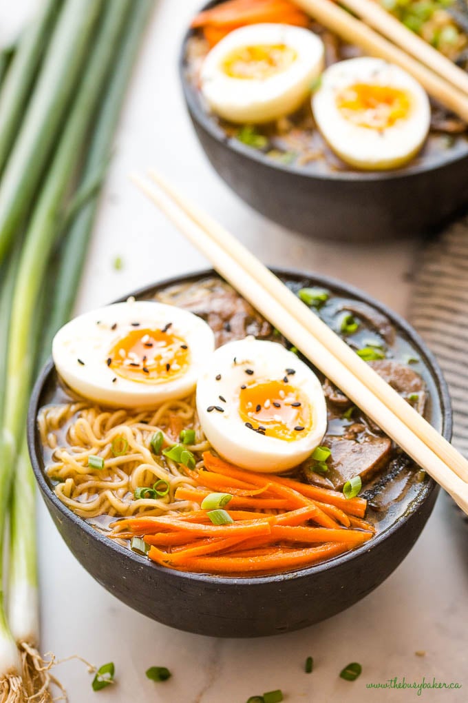 closeup image: vegetarian ramen with eggs, carrots, noodles, green onions, and chopsticks