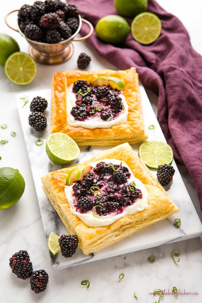 blackberry lime tarts on a marble board with fresh blackberries and lime zest