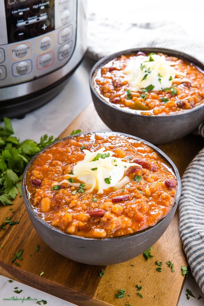 black bowl full of chili with sour cream and cheese