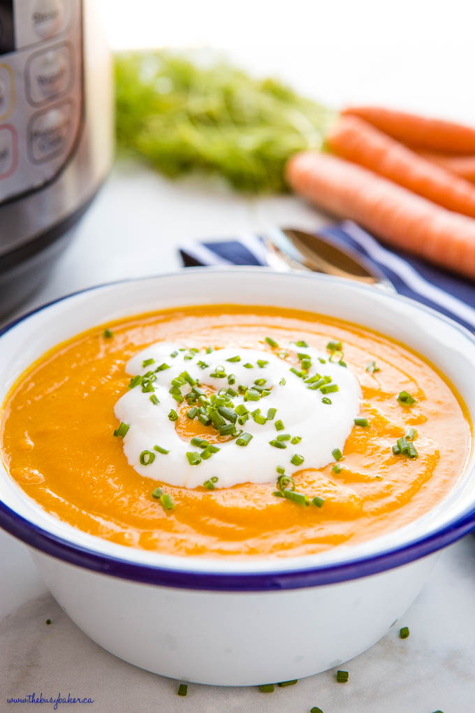 close up photo of carrot ginger soup with coconut cream and chives