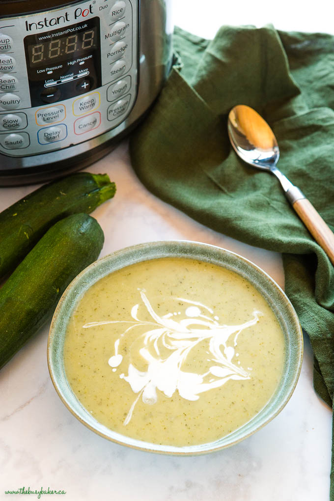 instant pot with creamy zucchini soup in a green bowl 