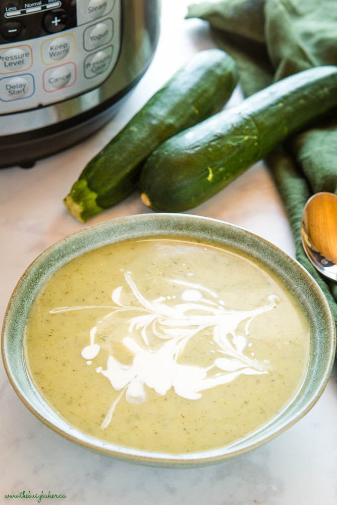 green bowl with zucchini soup and cream