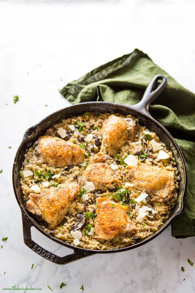 large cast iron pan with creamy mushroom rice and chicken thighs