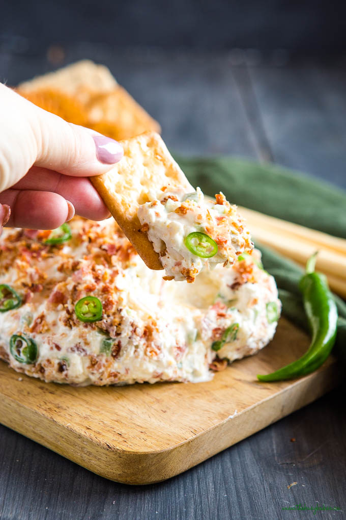 hand holding cracker with jalapeno cheddar bacon cheese ball