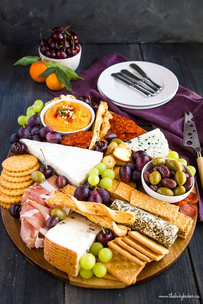 charcuterie board with olives, meat, cheese, crackers, grapes and cherries